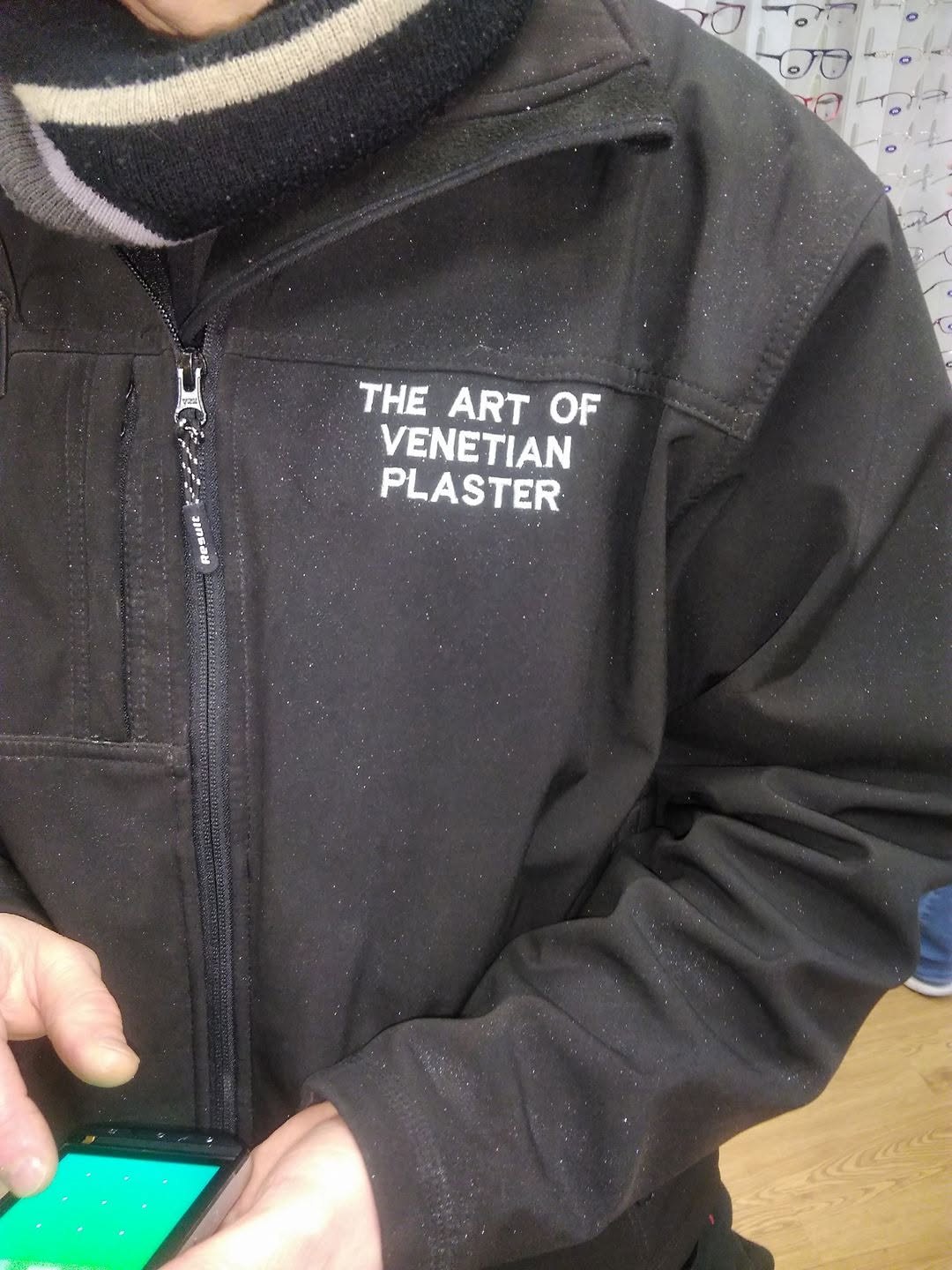 A black work jacket embroidered The Art of Venetian Plaster, covered in glitter from the day's work