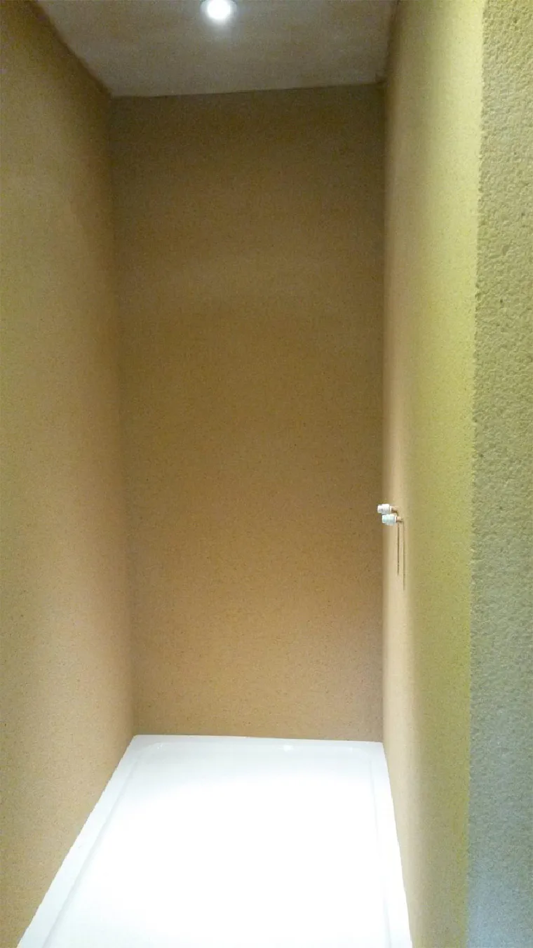 A shower recess finished seamlessly in a sand-coloured York stone effect, straight down to the tray