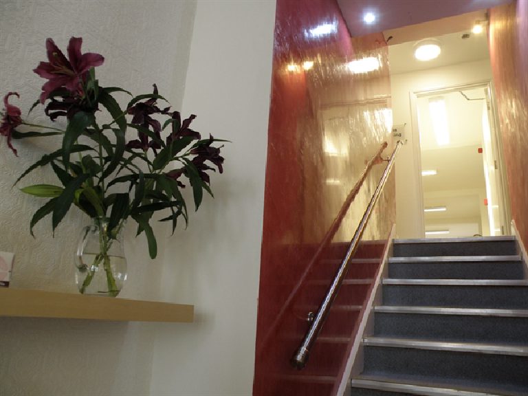 A deep red Lucidato stairwell, polished until it returns the ceiling lights.