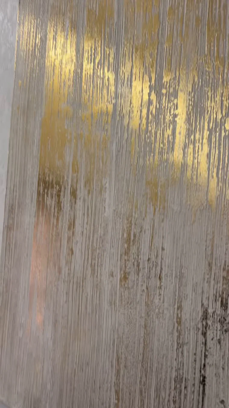 Gold transfer foil sitting on the raised ridges of a combed plaster texture