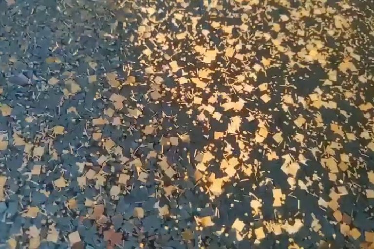 Bronze flake scattered through black, close up.