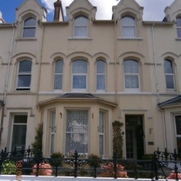 A cream elevation on the same terrace, arched window heads over a canted bay
