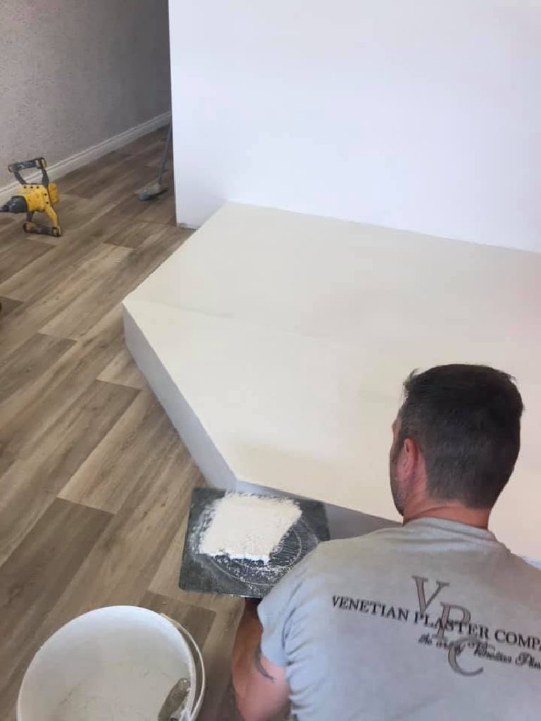 Plastering the pedicure plinth by hand, mortar board and bucket alongside, before the salon was fitted out