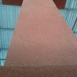 The cross head finished in terracotta render, seen from below under the scaffold roof