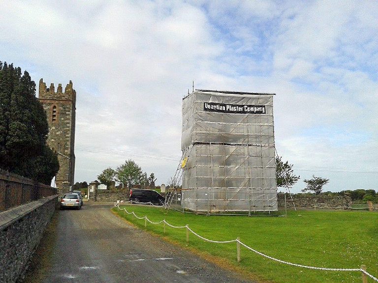 The memorial sheeted in and scaffolded from the ground up, the church tower alongside
