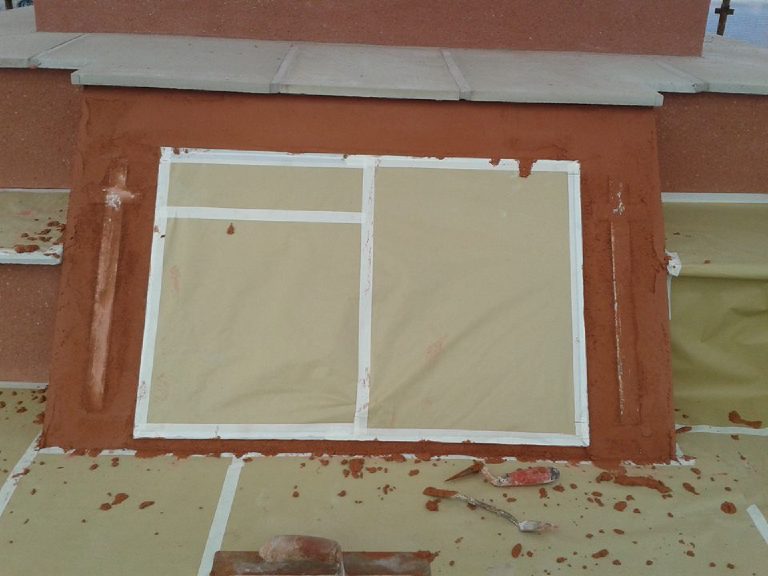 Wet terracotta render laid up to a masked off plaque, with a cross formed either side