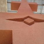 Looking up the rendered shaft to the cross, with a pointed motif recessed into the terracotta