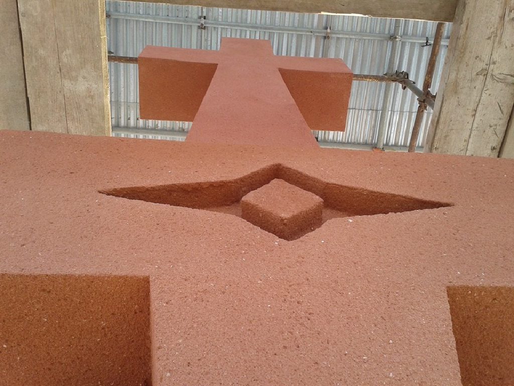 Looking up the rendered shaft to the cross, with a pointed motif recessed into the terracotta