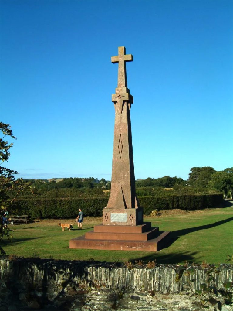The memorial before work started, weathered and pale, standing on its stepped red stone base