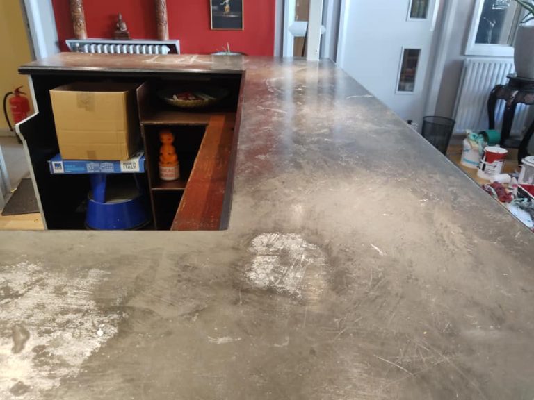 The grey microcement base coat on the bar top with trowel marks still showing