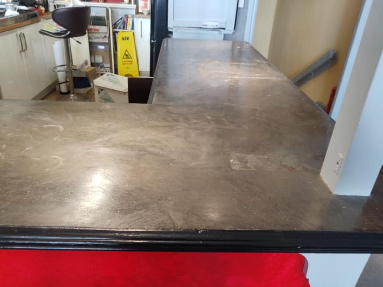The grey base coat seen from the customer side of the bar with the black edge moulding below