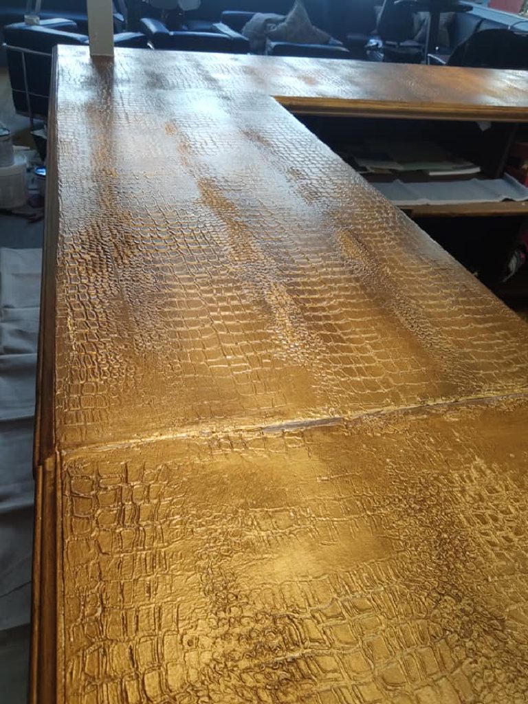 The bar top where two surfaces meet, showing the darker bronze streaks pulled through the gold