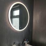 The basin and backlit round mirror against the metallic silver wall