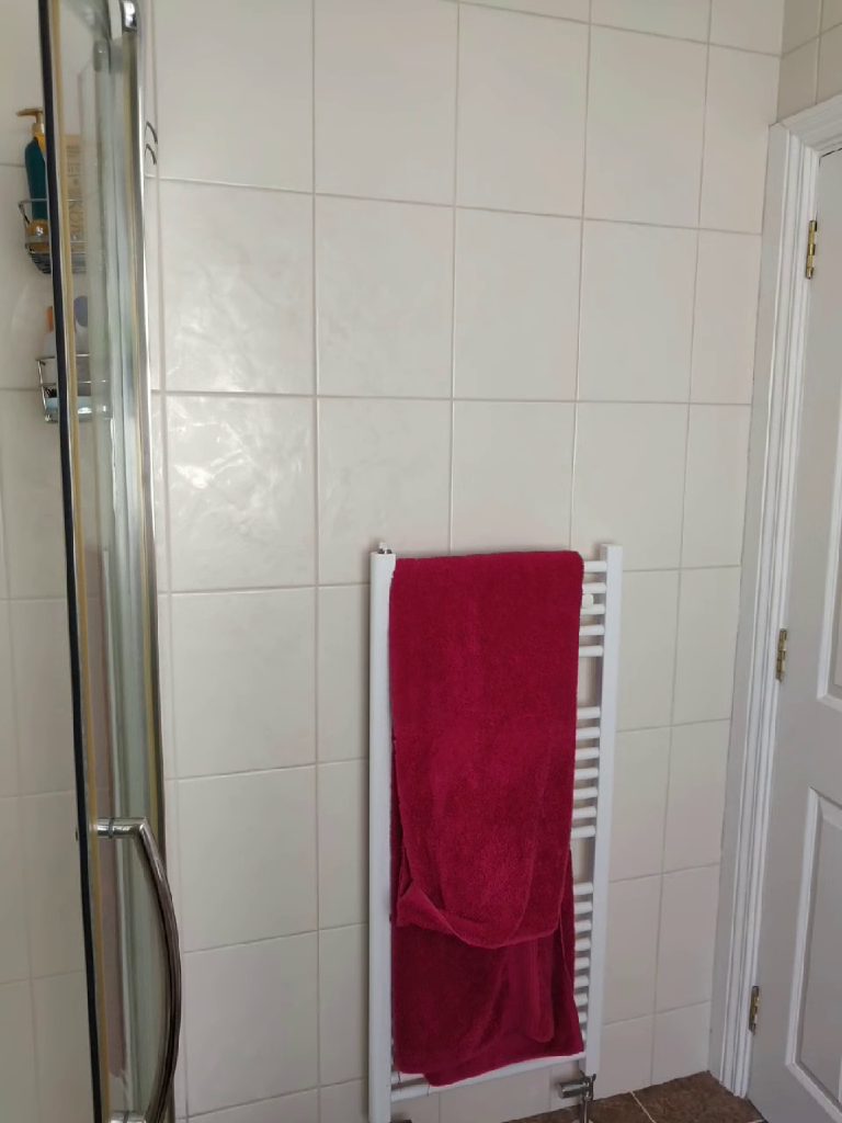 The white tiled wall and towel rail before the work