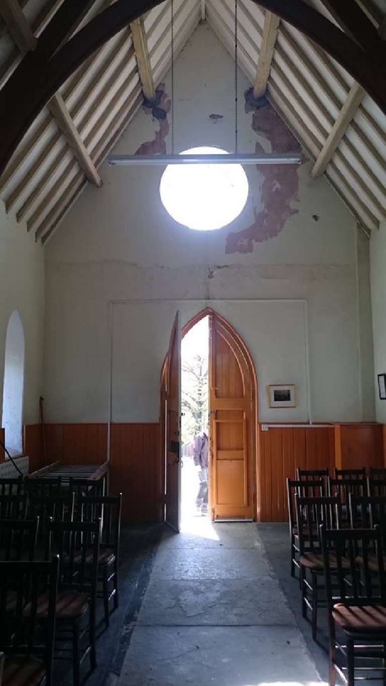 The chapel interior before the work — plaster flaking around the roof apex and the round window