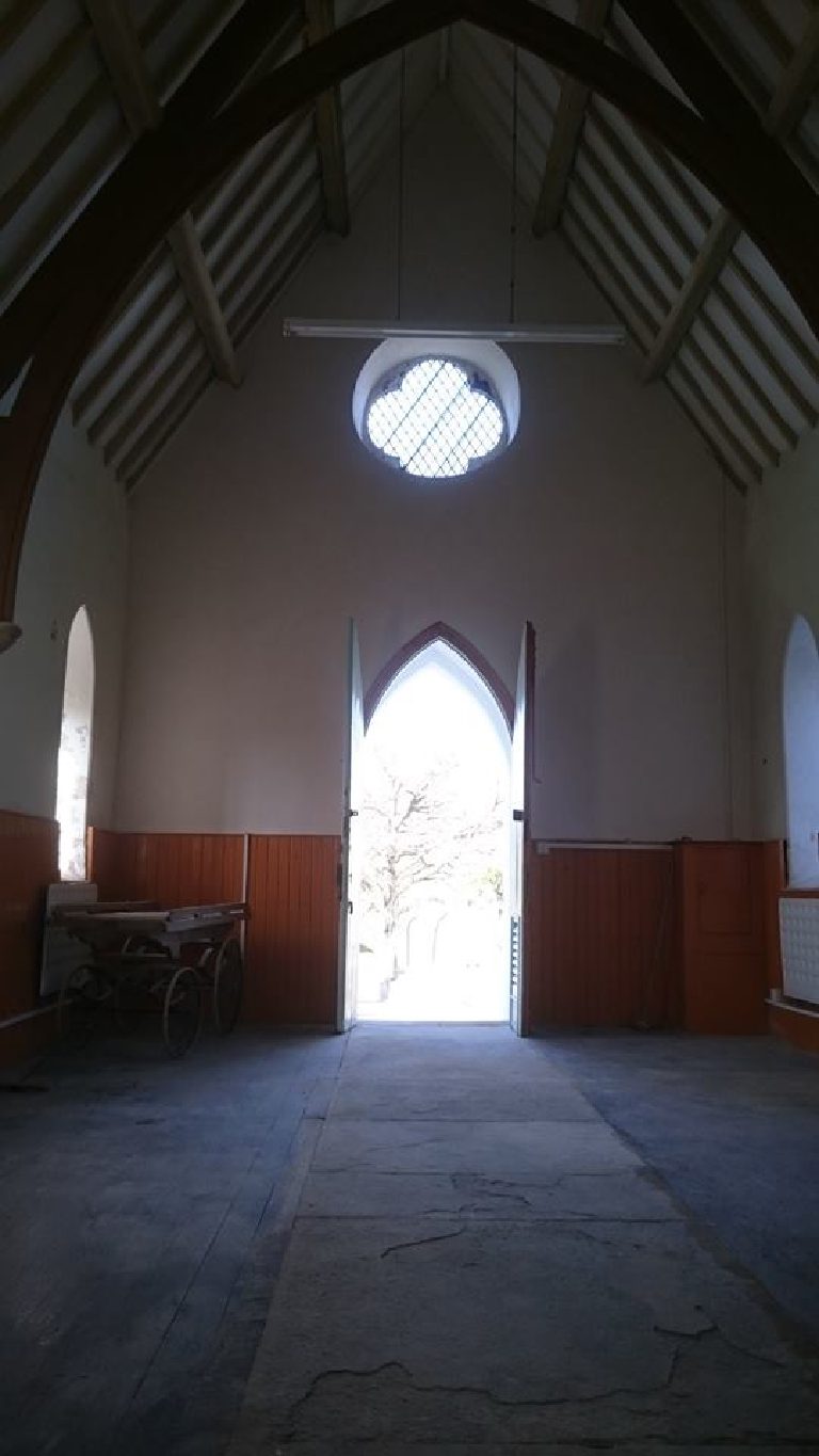 Inside the chapel looking back to the open door, round window above, flagged floor below