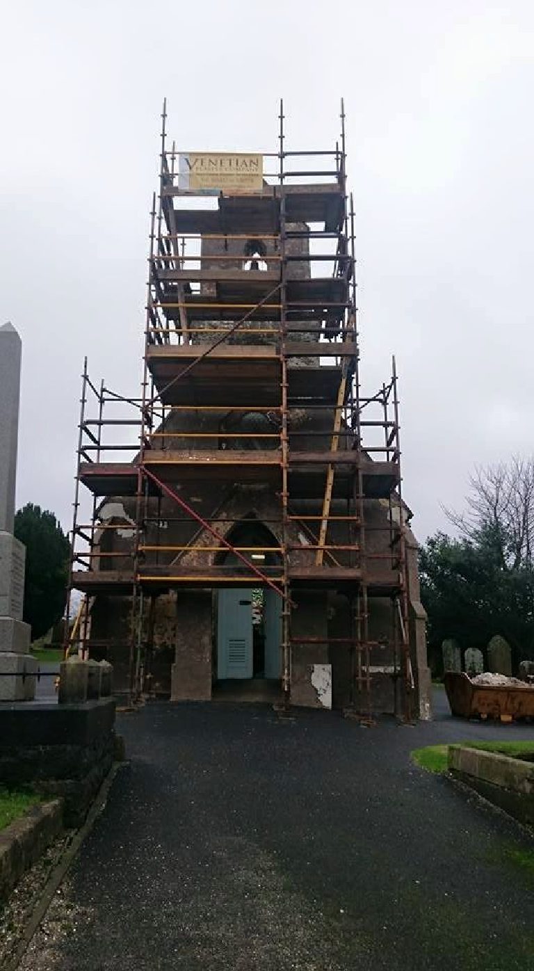 Scaffolding to the full height of the bell tower, the walls patchy where the old coating has come off