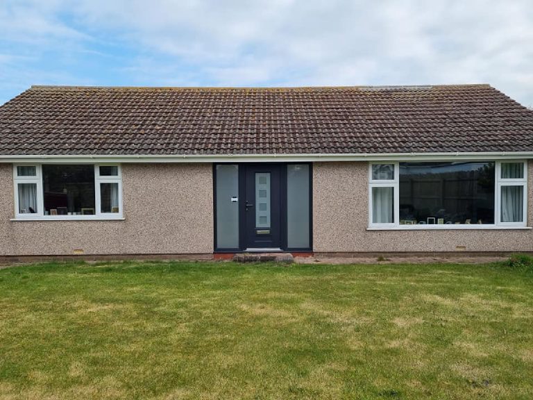 The front of the bungalow before the work, in pinkish spar dash under a brown tiled roof