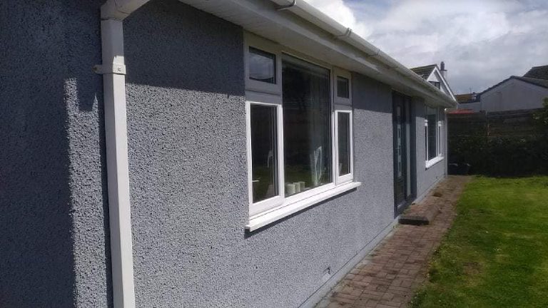 The side elevation in grey cork render, the texture picked out by raking sunlight