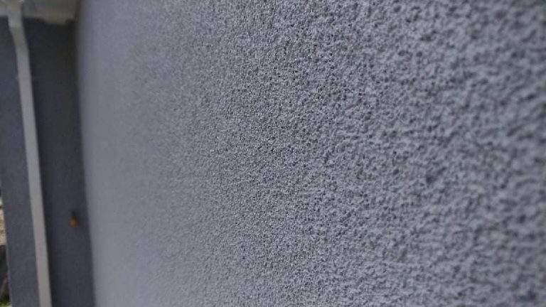 Close on the grey cork render, the granular texture running away from the edge