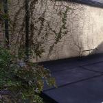 The finished conservatory roof in dark grey cork render, seen from above between the houses