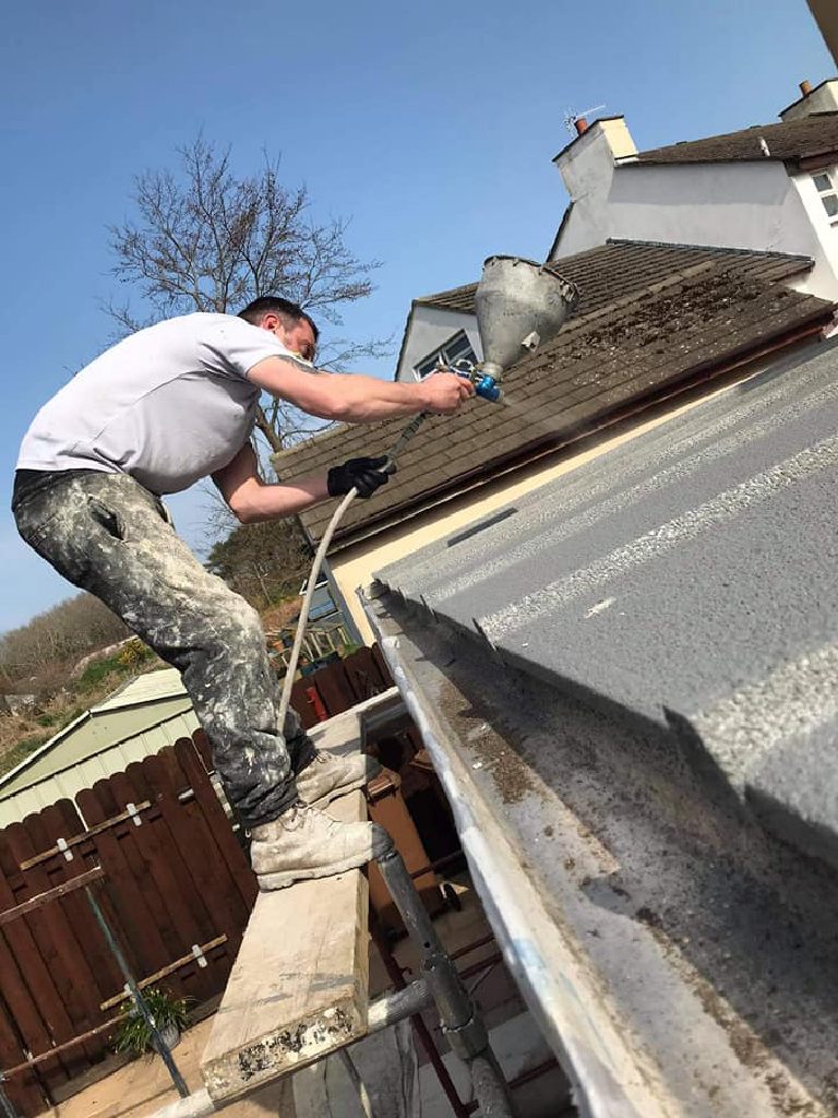 Spraying the cork render along the edge of the roof from a tower at the eaves