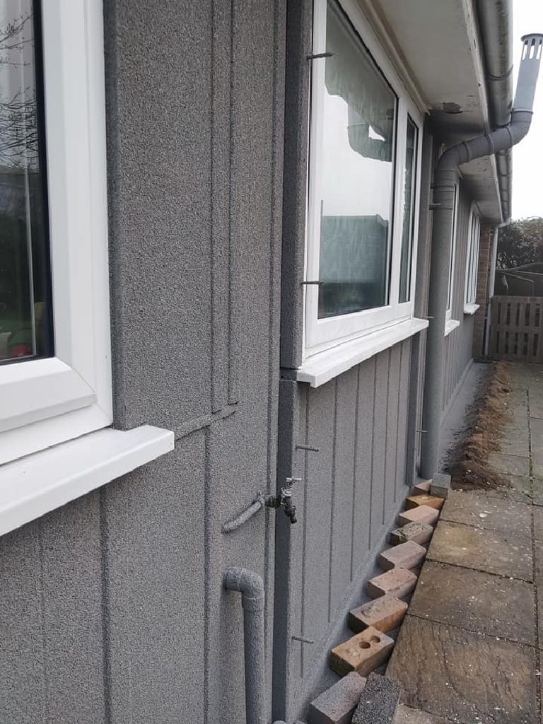 The downpipe and outside tap sprayed in the same grey as the wall behind them