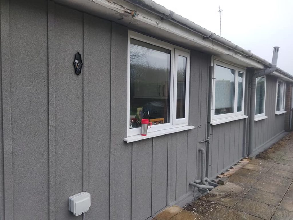 The finished bungalow in grey ThermoCork render, windows and sills picked out in white