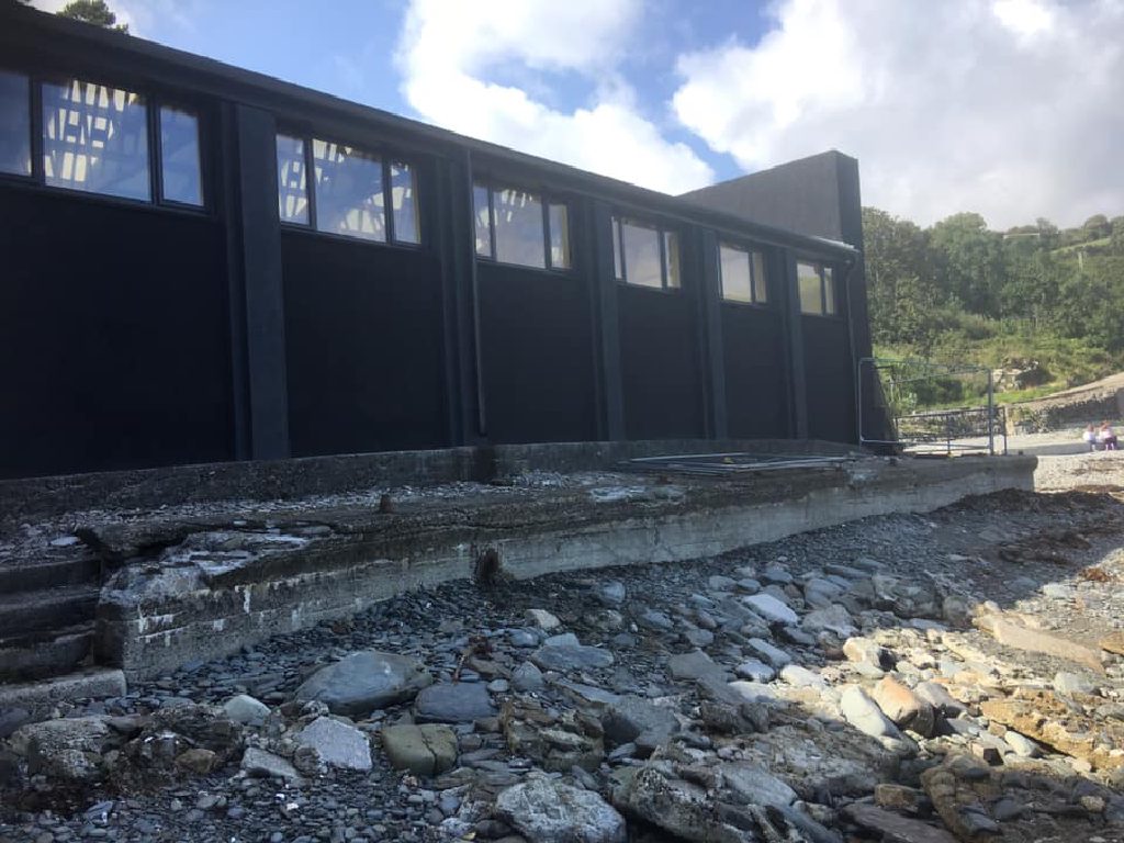 The rendered building seen along the shoreline