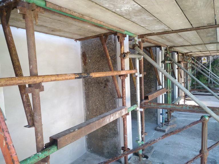 Scaffold running the length of the building with the bare walls behind