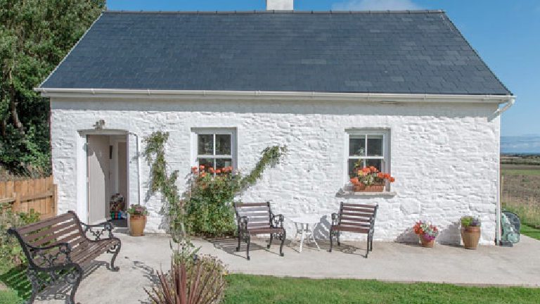 The finished cottage in white against a blue sky