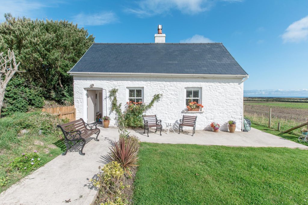 The finished cottage from the garden, benches out on the patio