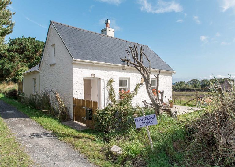 The cottage seen along the track, nameboard in the foreground