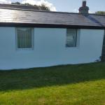 The cottage wall finished in white Wetherby thin coat render with a silicone top coat