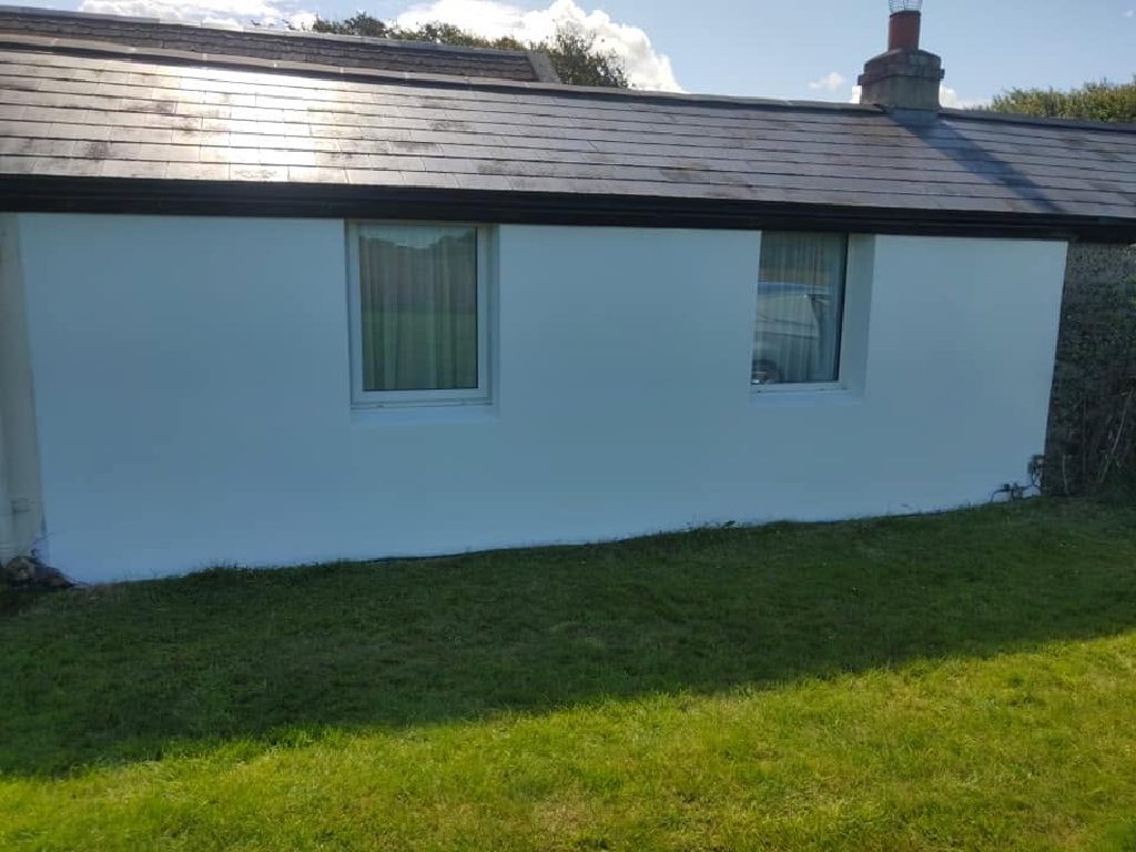 The cottage wall finished in white Wetherby thin coat render with a silicone top coat