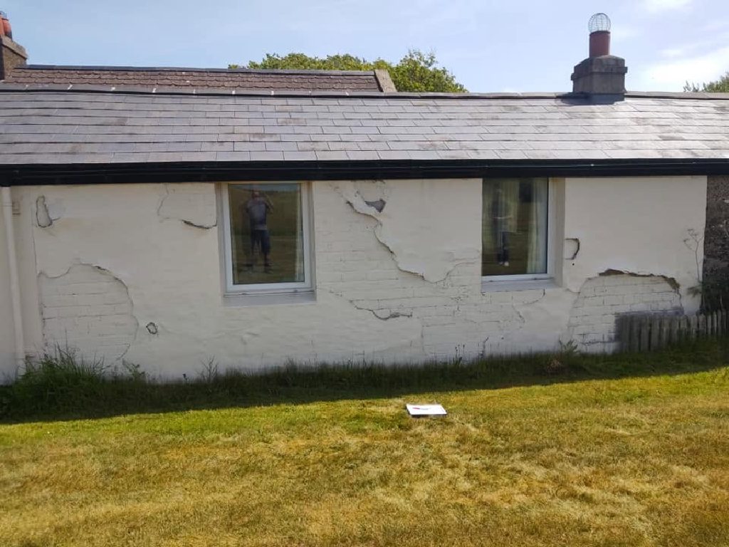 The cottage wall before work, old render lifting and peeling away in sheets