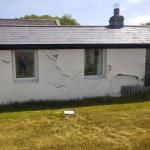 The cottage wall before work, old render lifting and peeling away in sheets