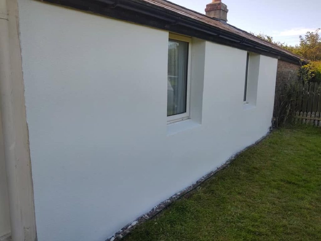 The rendered wall seen along its length, crisp window reveals and a gravel line at the base