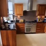 The whole kitchen from the doorway, quartz floor running wall to wall and a dark quartz splashback behind the range