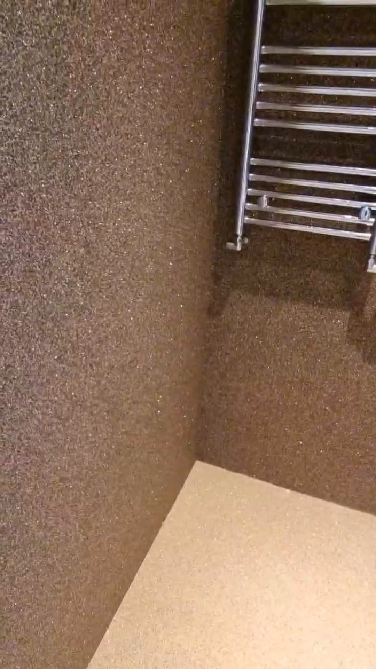 The internal corner of the W.C. where the two bronze walls meet the sand-coloured floor