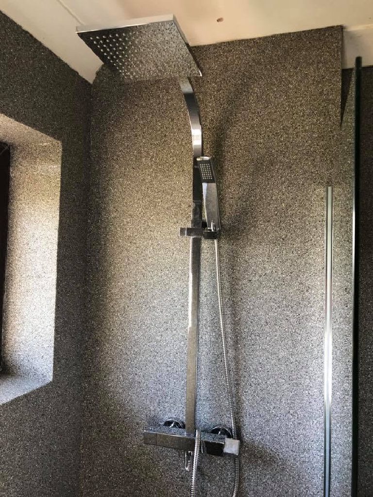 The shower running straight onto the quartz wall with no tile or trim