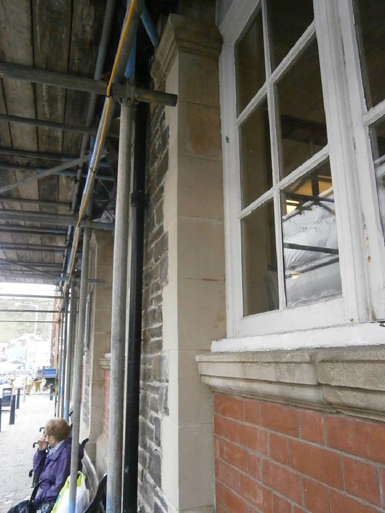 Street level beneath the scaffold walkway, with a freshly repaired corner pier