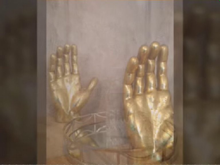 Gold hand sculptures set against the plastered wall