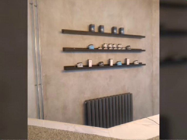 Product shelves and a column radiator against the concrete-look wall