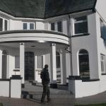 The finished house in crisp white render with black trim, plasterer at the door