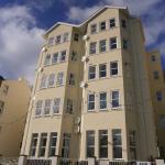 Full frontage of Falcon Cliff Apartments in fresh cream render under a blue sky