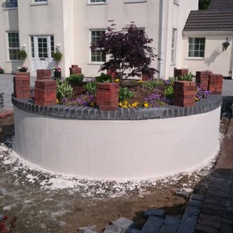 The rendered curve seen from the drive with the house behind, render splashes still on the ground