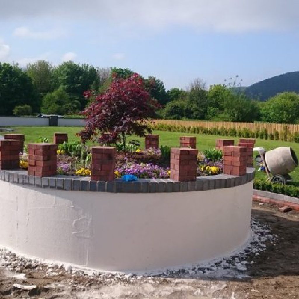 The curved wall freshly rendered, render splashes still on the ground around it