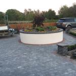 The finished raised bed — smooth white render, dark soldier course coping, an acer and bedding plants inside