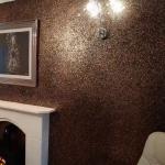 The bronze and black feature wall with the fireplace and wall lights